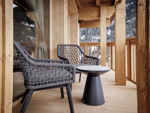 A wooden deck with two wicker chairs and a table. - Leni Mountain Lodge (Soelden)
