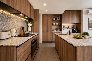 A modern kitchen with wooden cabinetry, a gas stove, and a built-in oven. - 19F Sky-Rise 2BR 2BTH, Panoramic CBD Views with Resort-Style Amenities (Carlton)