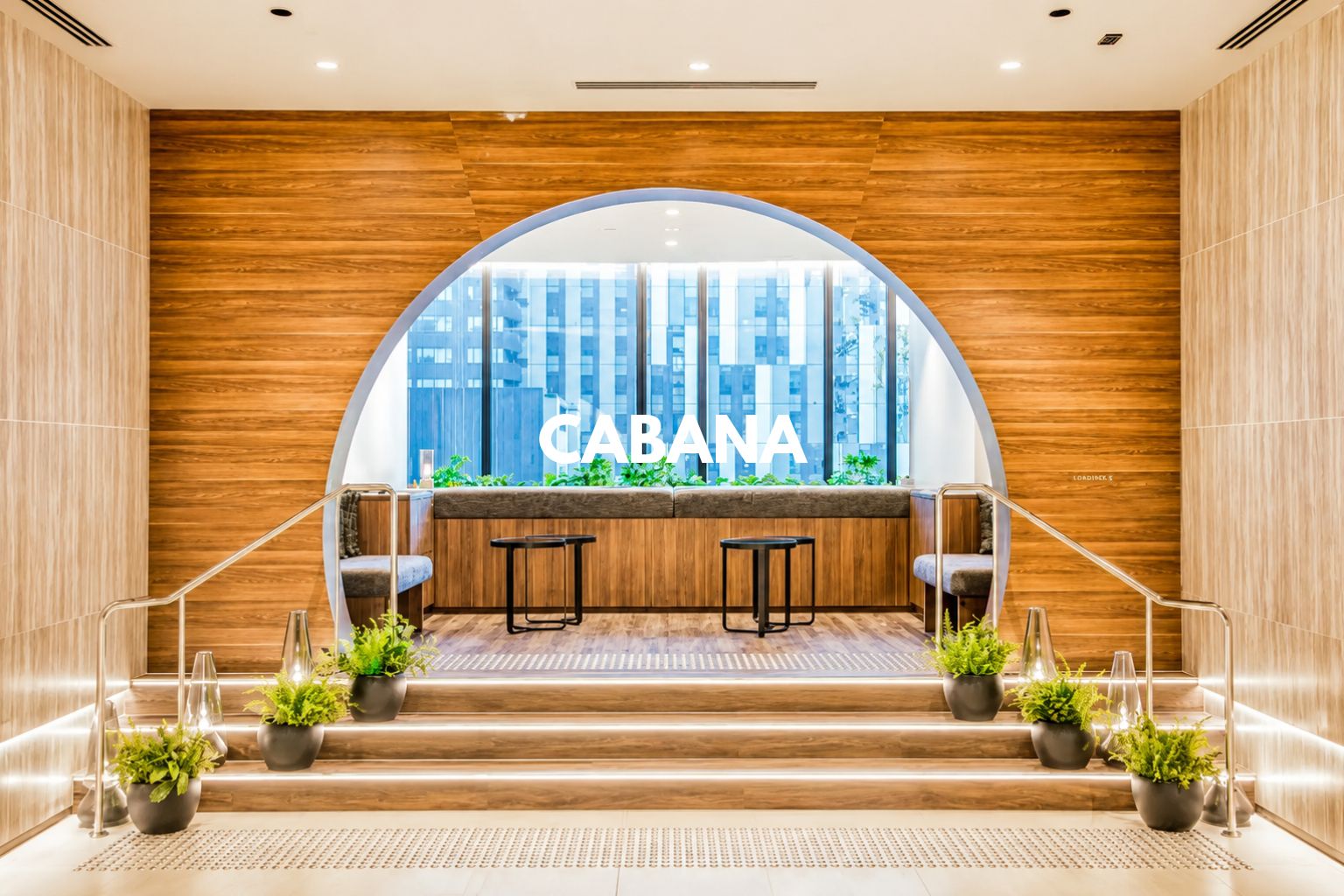 A modern interior with a wooden wall, a large arched window, and a seating area with two tables and chairs.