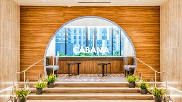 A modern interior with a wooden wall, a large arched window, and a seating area with two tables and chairs.