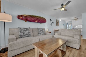 Ein Wohnzimmer mit zwei Sofas, einem Couchtisch und einem Deckenventilator.