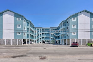Ein mehrstöckiges Motel mit einem zentralen Eingang, Balkonen und einem Parkplatz.
