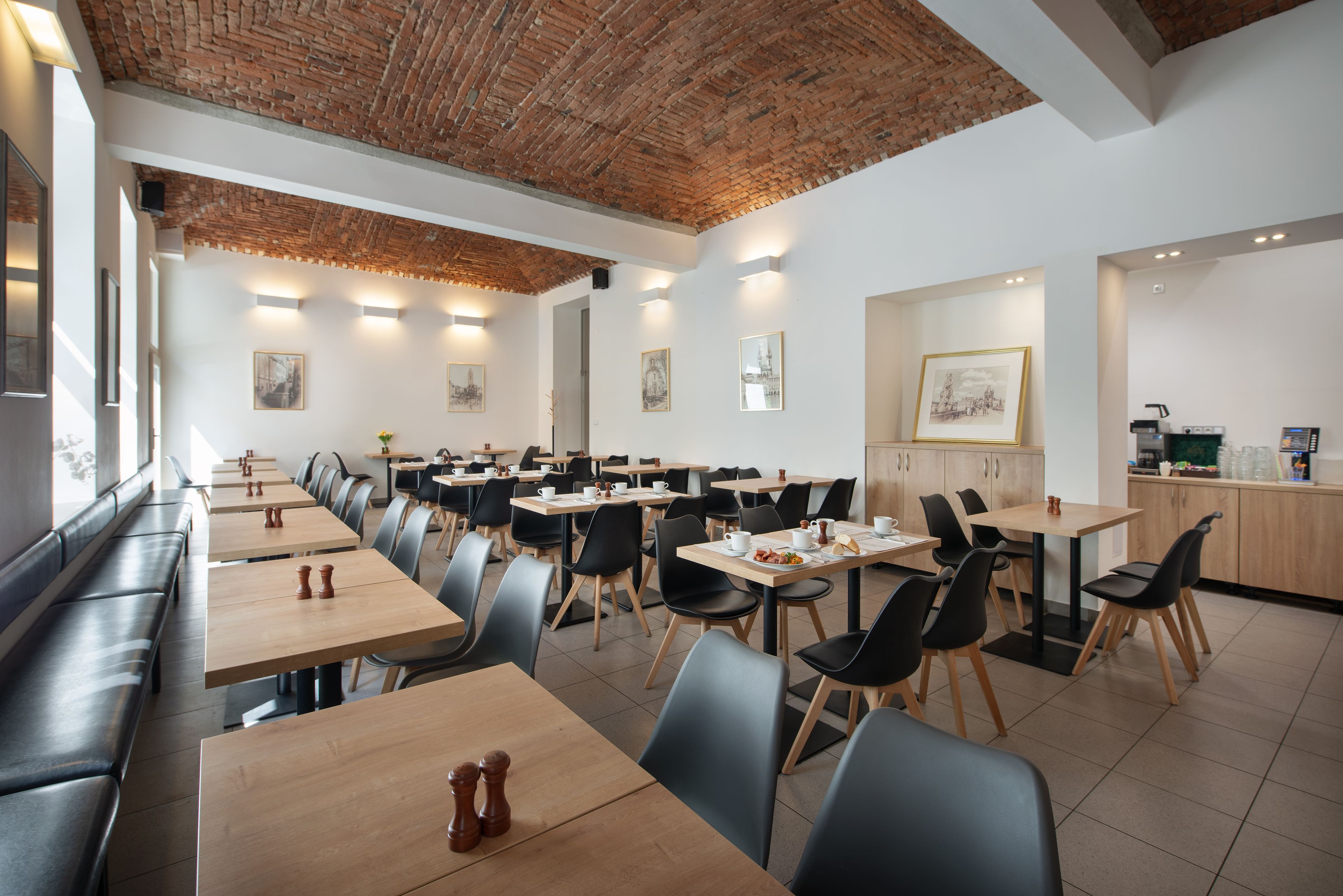 A restaurant with multiple tables and booths, brick ceiling, and wall-mounted artwork.