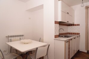 Eine kompakte Küche mit weißer Arbeitsplatte, Spüle und Spritzschutz mit Rautenmuster.