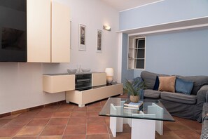 Ein modernes Wohnzimmer mit einem Glastisch, einer Couch, einem Flachbildfernseher und einem Schrank.