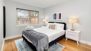 A bedroom with a bed, bedside tables, a window, and a painting on the wall. - @ Marbella Lane - Immaculate & Cozy 3BR Home (San Jose)