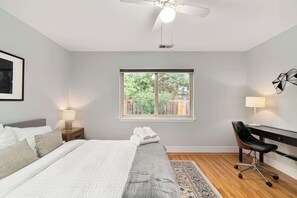 A bedroom with a bed, bedside lamps, a desk, and a window with a view of greenery. - @ Marbella Lane - Immaculate & Cozy 3BR Home (San Jose)