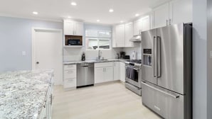 A modern kitchen with white cabinets, stainless steel appliances, and a granite countertop. - @ Marbella Lane - Immaculate & Cozy 3BR Home (San Jose)