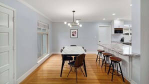 A modern kitchen with white cabinets, a marble countertop, and a hanging light fixture. - @ Marbella Lane - Immaculate & Cozy 3BR Home (San Jose)