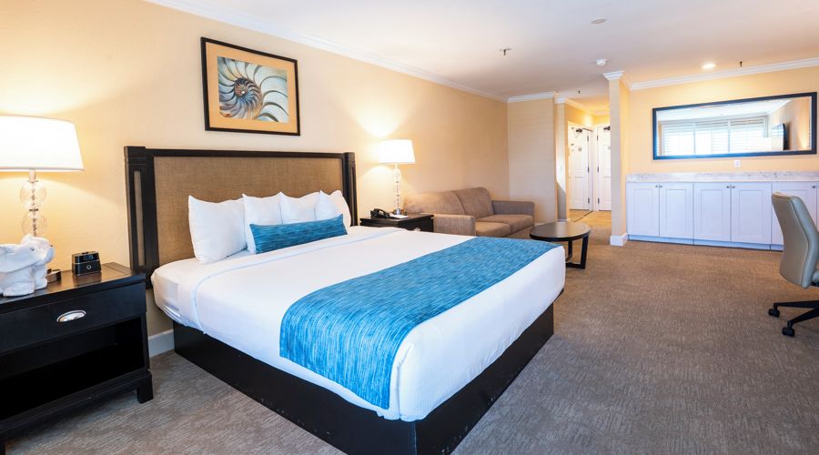 Een hotelkamer met een groot bed, een bureau, een stoel en een kitchenette.