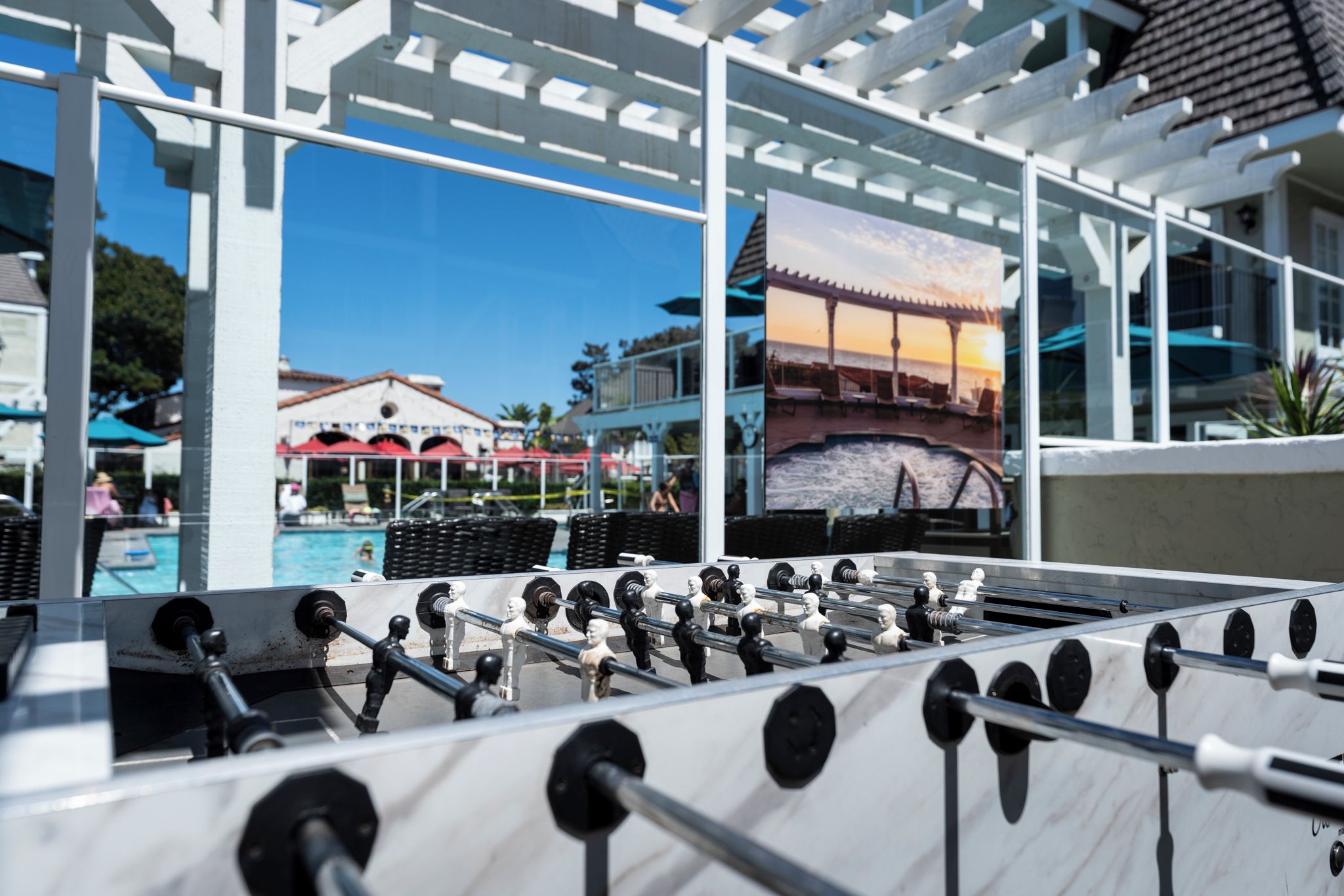 A foosball table with a view of a pool and outdoor seating area.