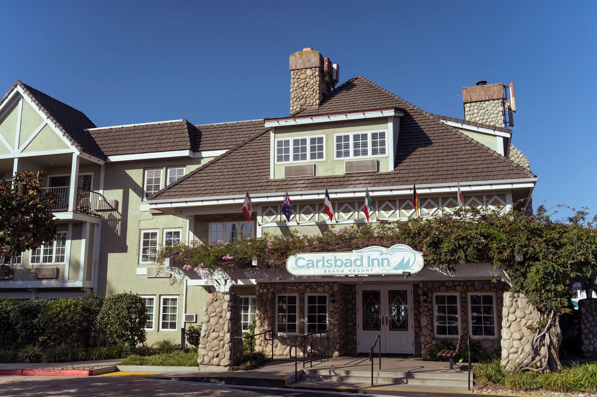 A multi-story building with a stone facade, multiple windows, and a sign indicating it is a beach resort.