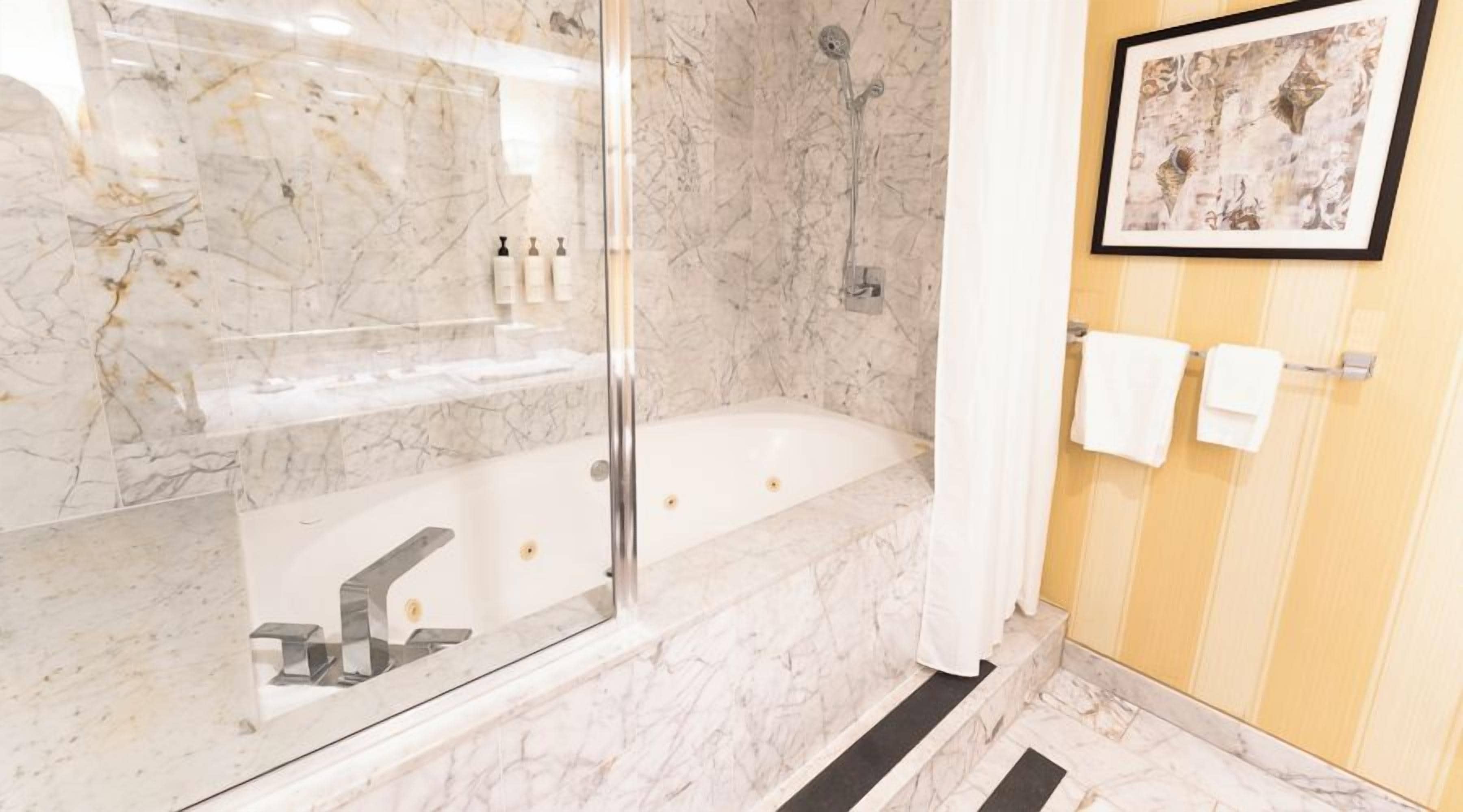 Ein Badezimmer mit Marmorwaschbecken, einer Badewanne und einer Dusche.