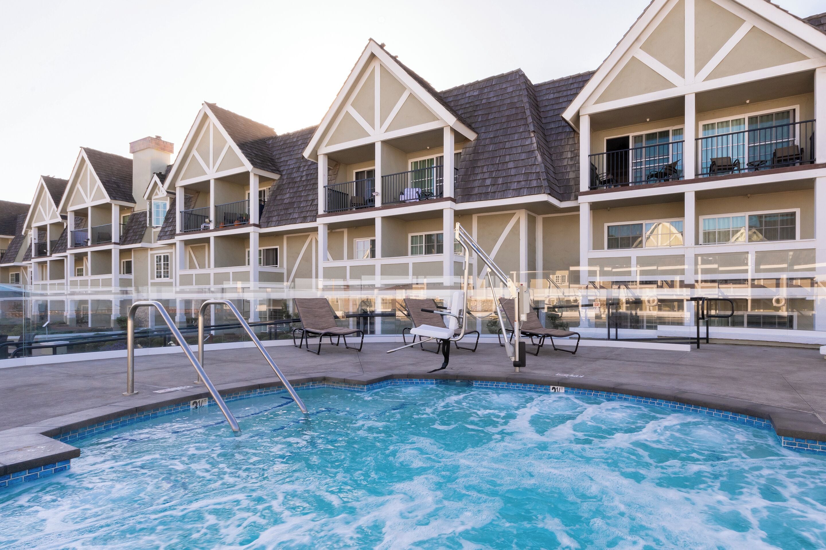 A hotel with a pool area, including lounge chairs and a staircase leading to the pool.