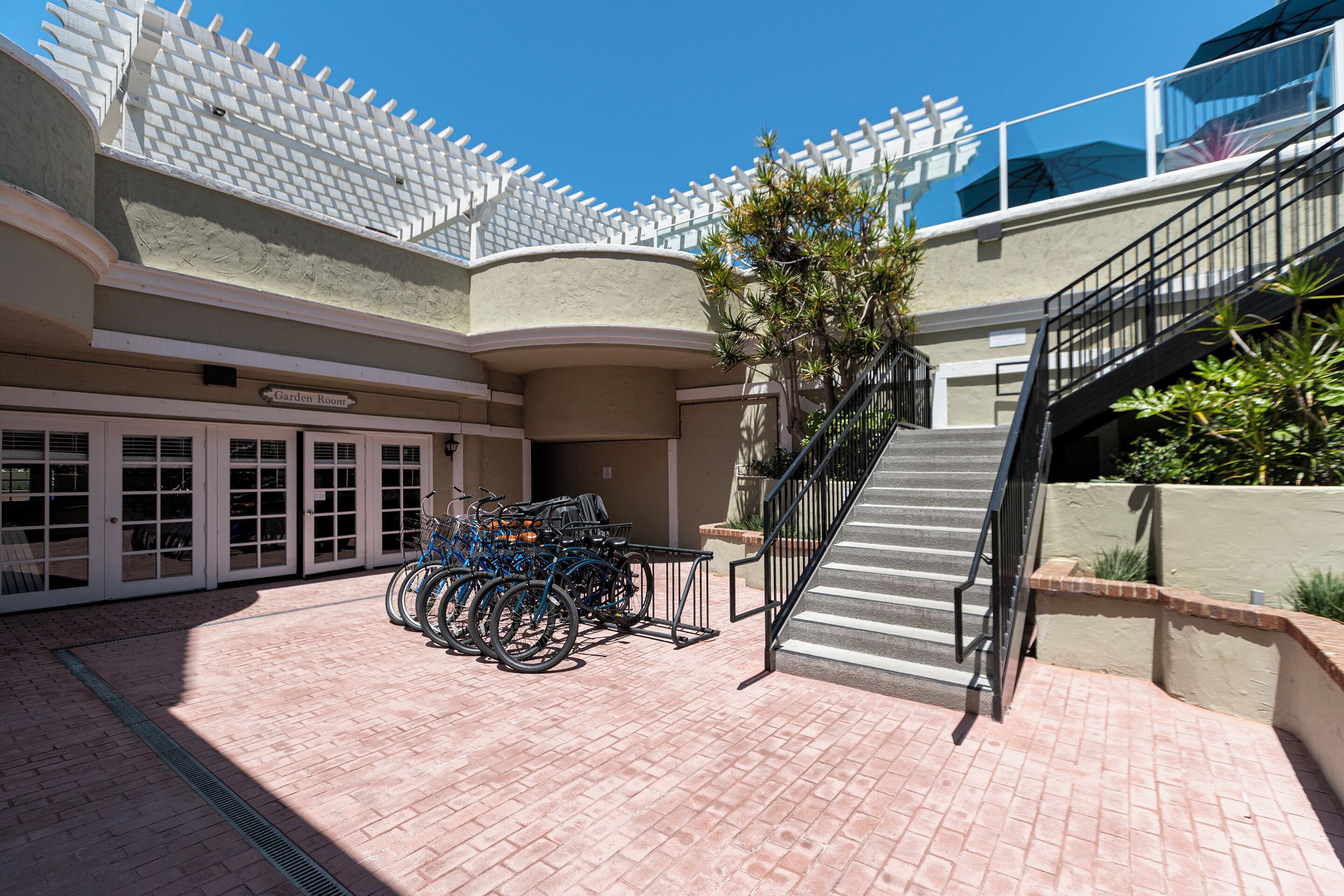 A courtyard with a bike rack, a staircase, and a sign labeled "Garden Room".
