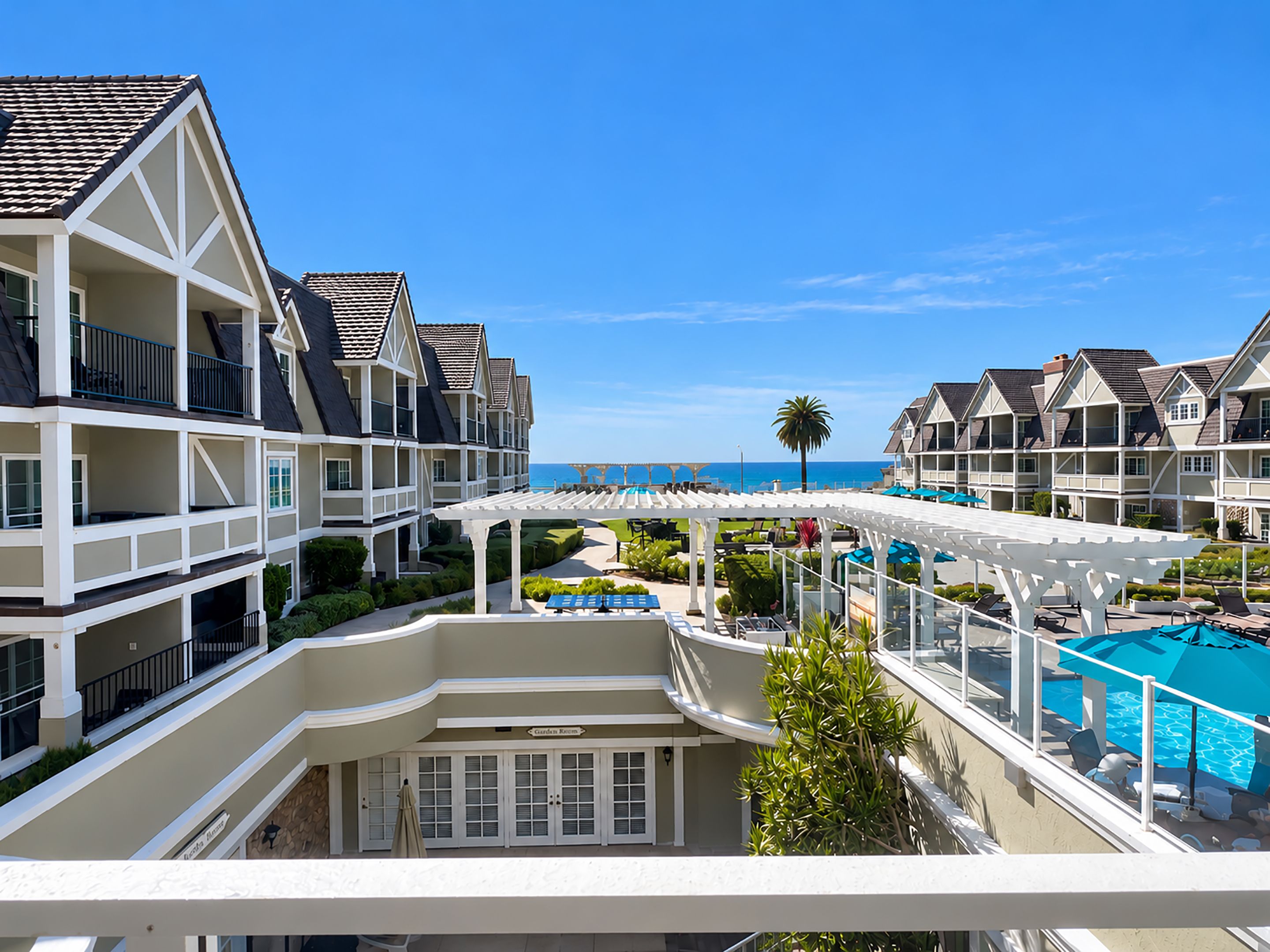 A resort with multiple-story buildings, a pool area, and a view of the ocean.