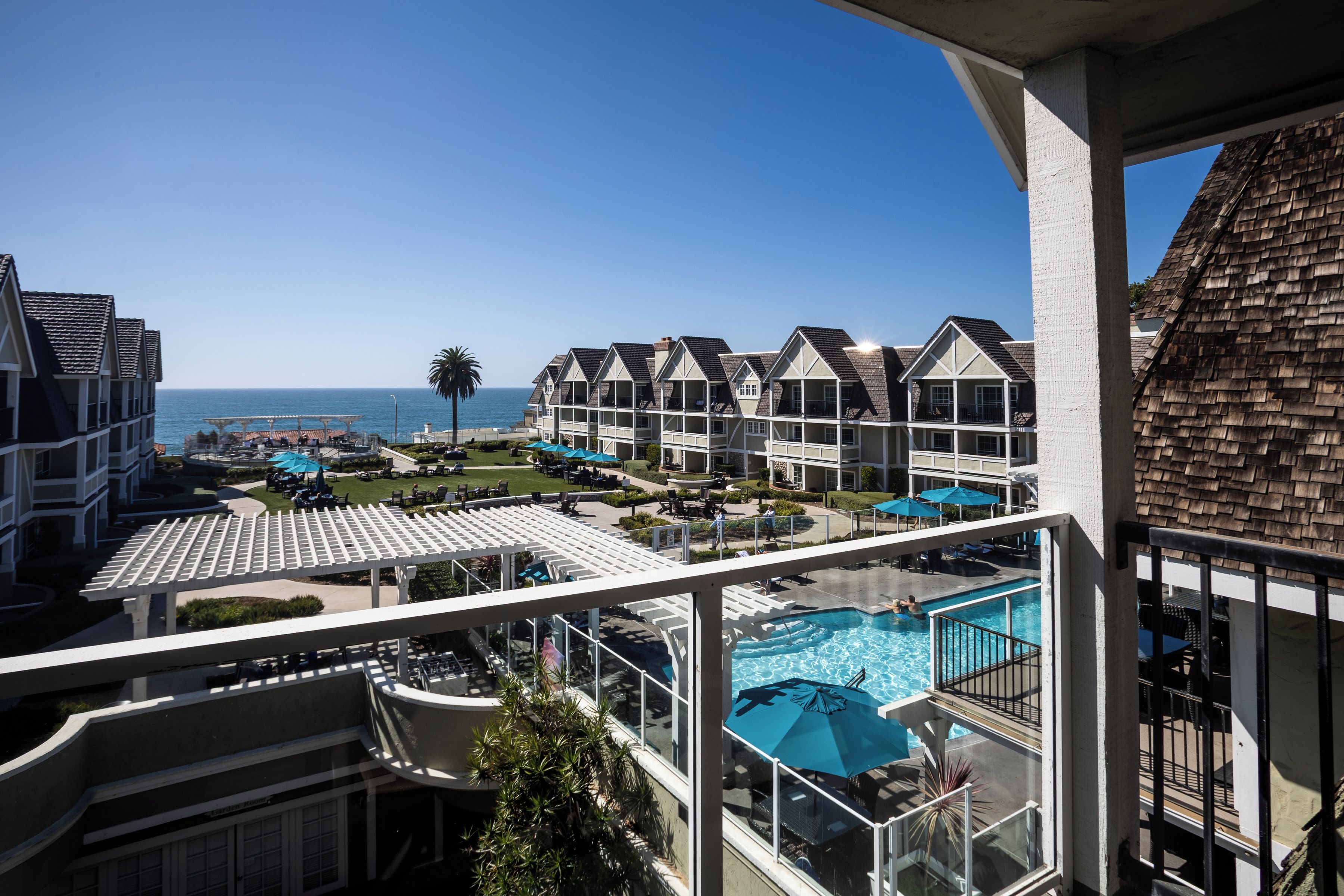 A resort with multiple-story buildings, a swimming pool, and a view of the ocean.