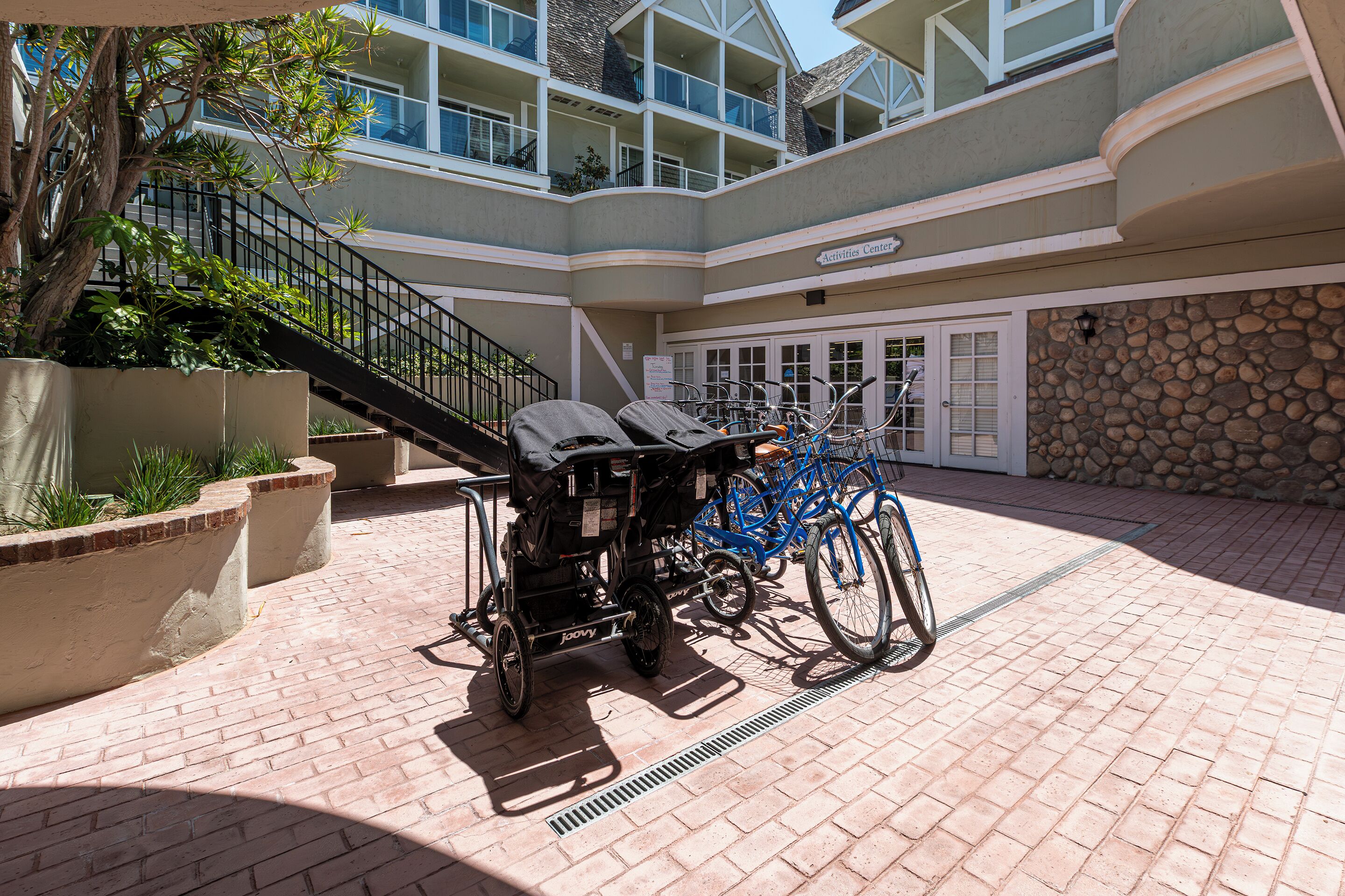 A courtyard with a stroller, a blue bicycle, and a stone wall.