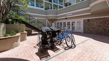 A courtyard with a stroller, a blue bicycle, and a stone wall.