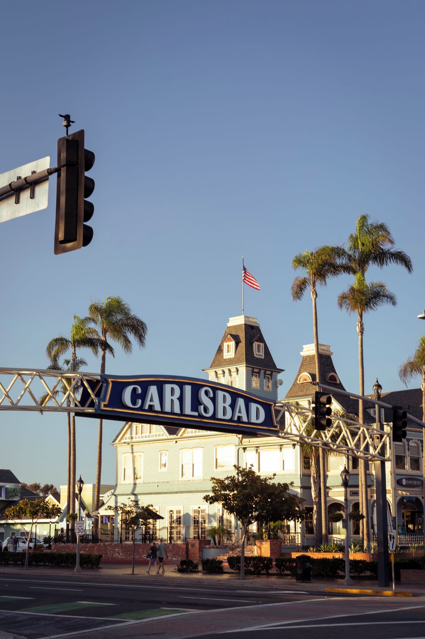 Un panneau de signalisation indiquant « CARLSBAD », un feu de circulation et un bâtiment sur lequel flotte un drapeau.