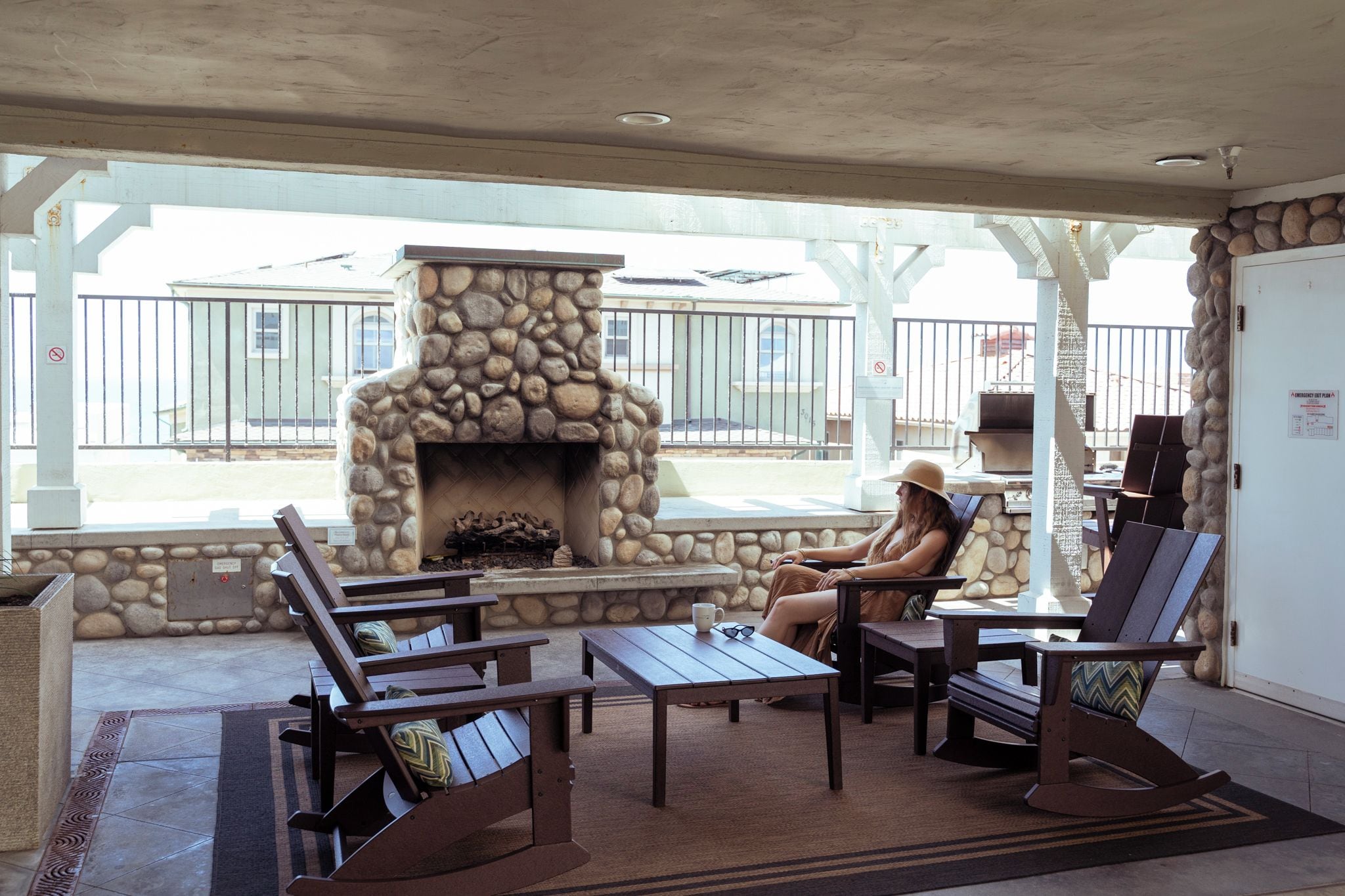Un espacio de estar al aire libre con paredes de piedra, una chimenea y vistas a la calle.