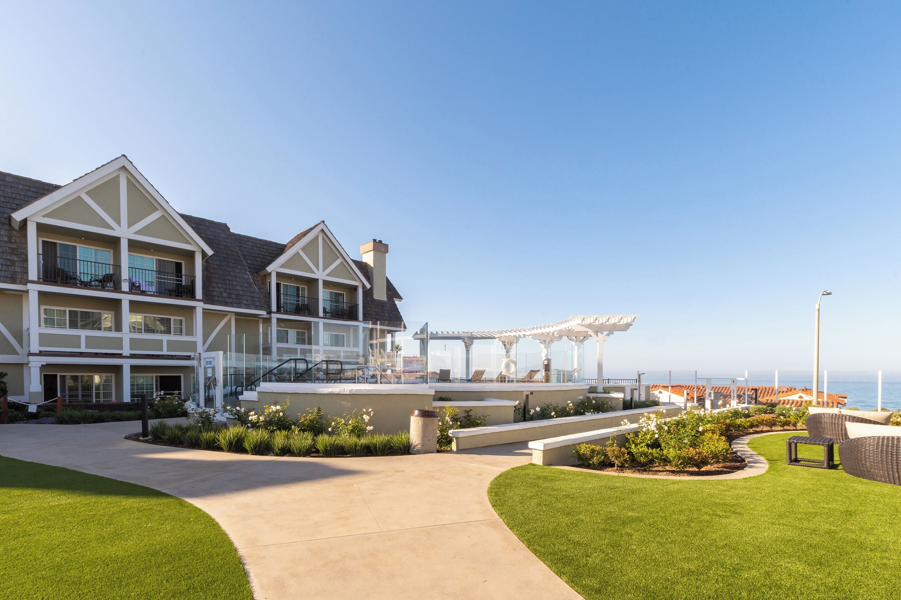 A large, multi-story hotel with a covered outdoor seating area and a view of the ocean.