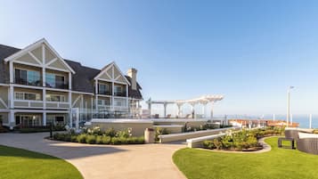 A large, multi-story hotel with a covered outdoor seating area and a view of the ocean.