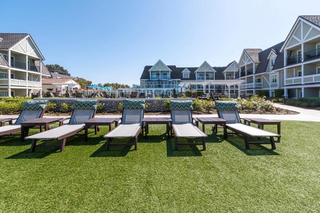 A resort with multiple-story buildings, a pool area with lounge chairs, and a well-maintained lawn.