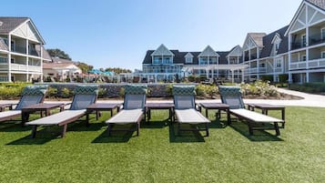 A resort with multiple-story buildings, a pool area with lounge chairs, and a well-maintained lawn.