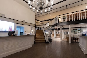 Eine geräumige Lobby mit einer Treppe, einem Empfangstresen und einem Chandelier.