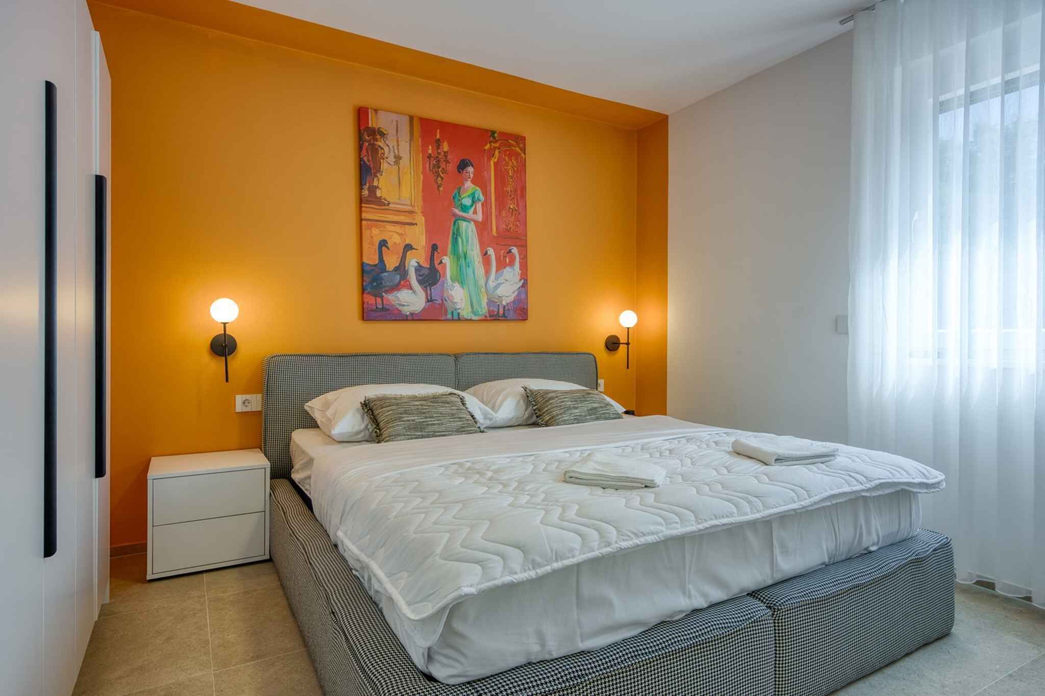 A bedroom with a large bed, two bedside tables, a painting on the wall, and a window with curtains.