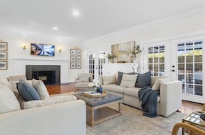 A spacious living room with a fireplace, comfortable seating, and a large window with a view.