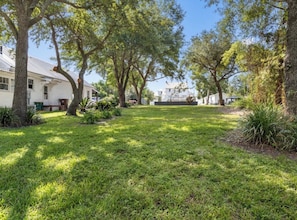A grassy yard with trees and a white building.