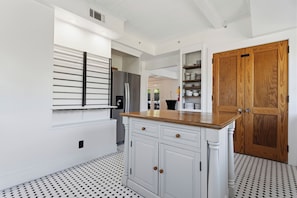 A kitchen with a white countertop, wooden cabinets, and a patterned floor.
