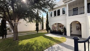 A white building with a storefront, a paved walkway, and a well-maintained lawn.