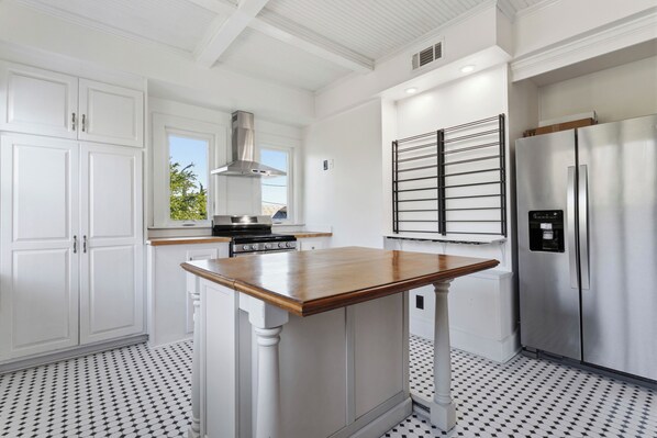 A kitchen with white cabinetry, a wooden island, a stainless steel refrigerator, and a patterned floor.