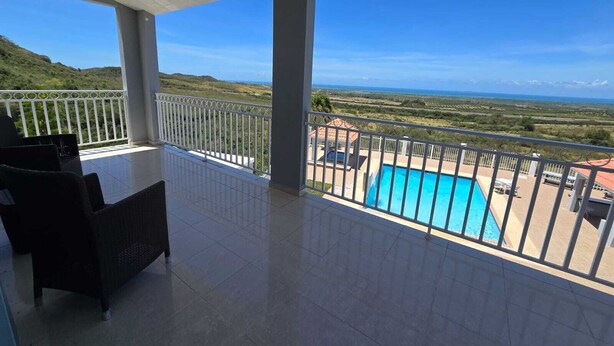 Un balcón con vistas a una piscina y un paisaje distante.