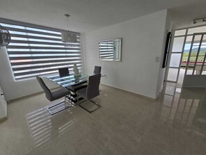 Uma área de jantar moderna com mesa de vidro, cadeiras e uma escultura decorativa.