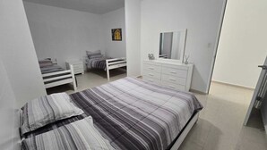 Un dormitorio con una cama, un aparador, un espejo y un cuadro pequeño en la pared.