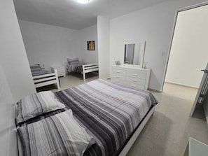 Ein Schlafzimmer mit einem Bett, einem Schminktisch, einem Spiegel und einem kleinen Bild an der Wand.