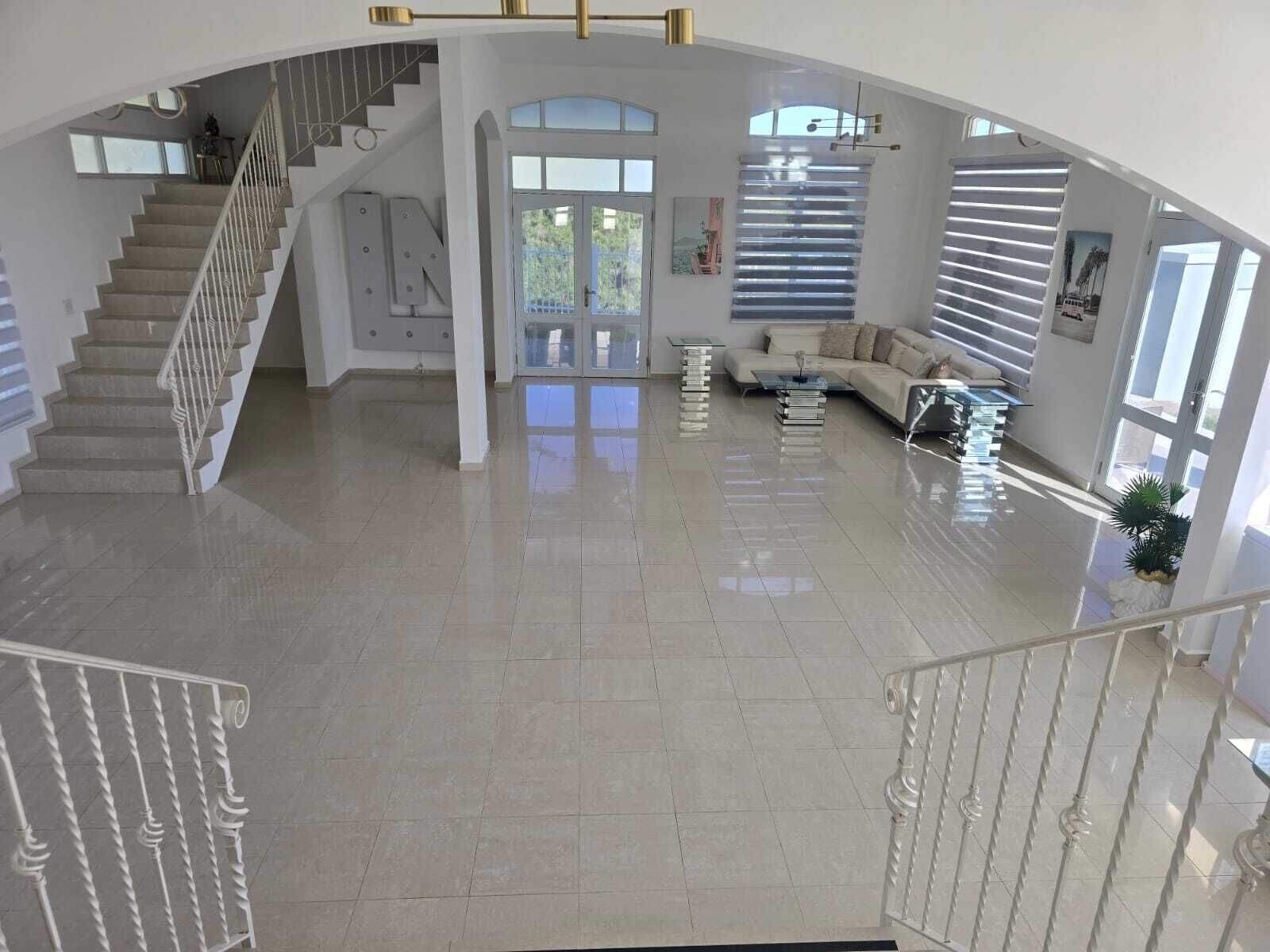 Amplia sala de estar con una escalera, un sofá y una mesa de centro.
