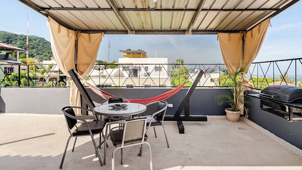 Um terraço no telhado com uma rede, uma mesa redonda e cadeiras.