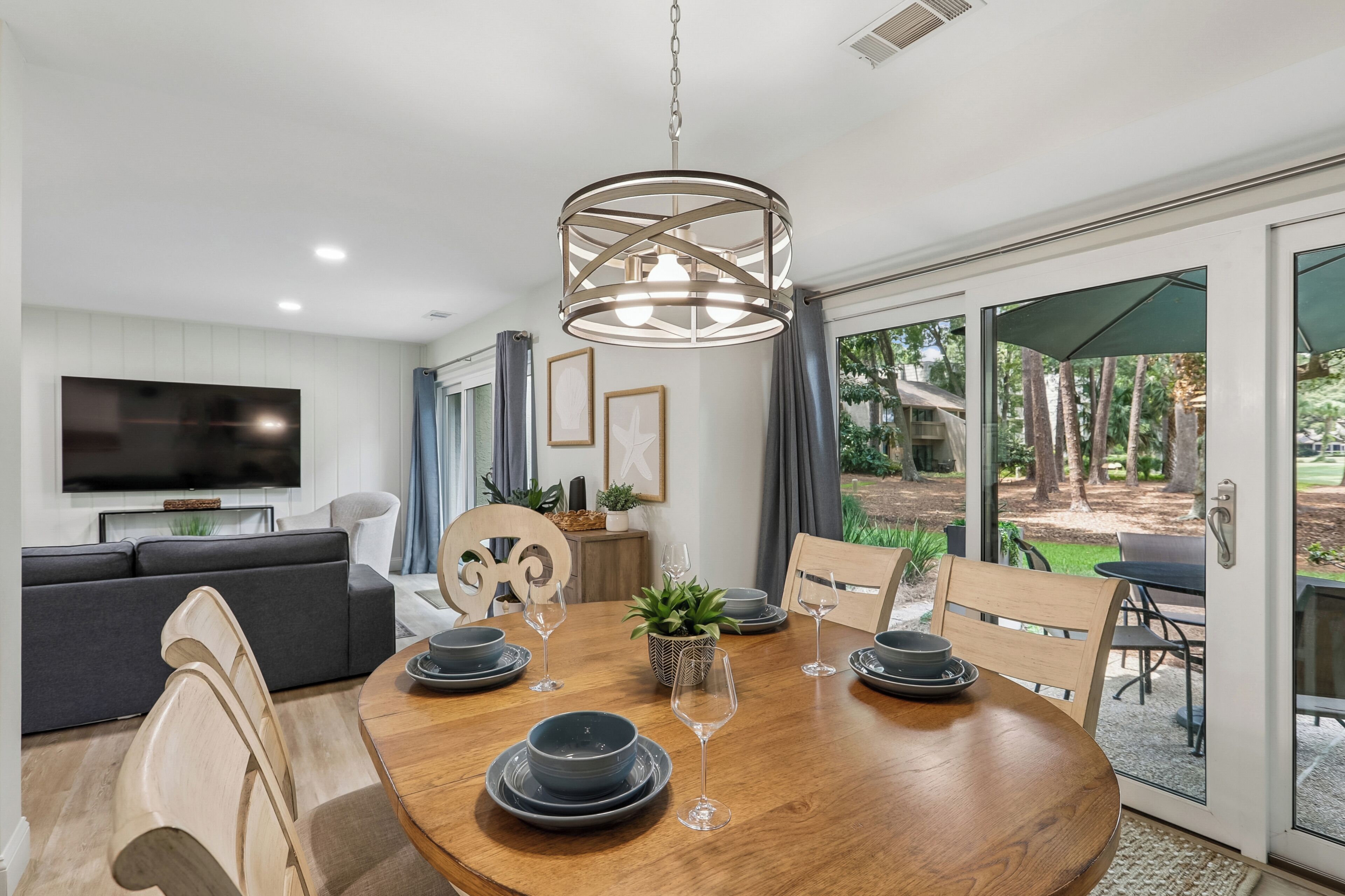 A modern dining area with a round wooden table, chairs, and a chandelier.