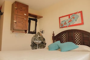 Een slaapkamer met een bed, een houten garderobe, een wastafel aan de muur en een decoratief schilderij.