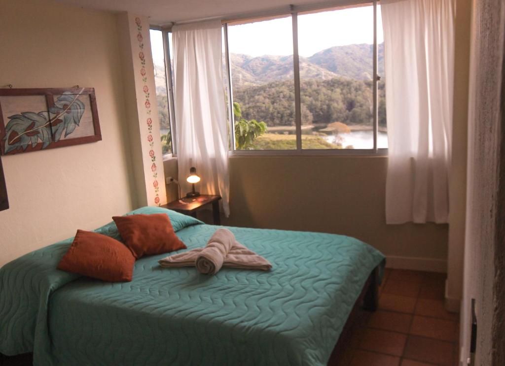 A bedroom with a bed, a nightstand, a lamp, and a window with curtains.
