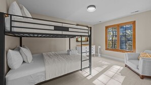 Ein Schlafzimmer mit Etagenbetten, Schreibtisch und Stuhl, einem Fenster mit Blick und einer Sitzecke.