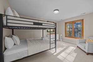 Ein Schlafzimmer mit Etagenbetten, Schreibtisch und Stuhl, einem Fenster mit Blick und einer Sitzecke.