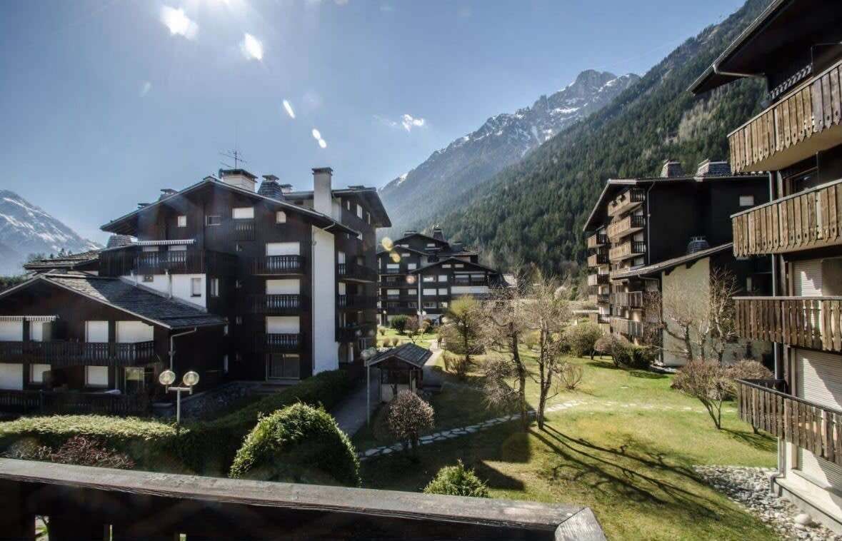 A mountain resort with multi-story buildings, a well-maintained garden, and a view of snow-capped mountains.