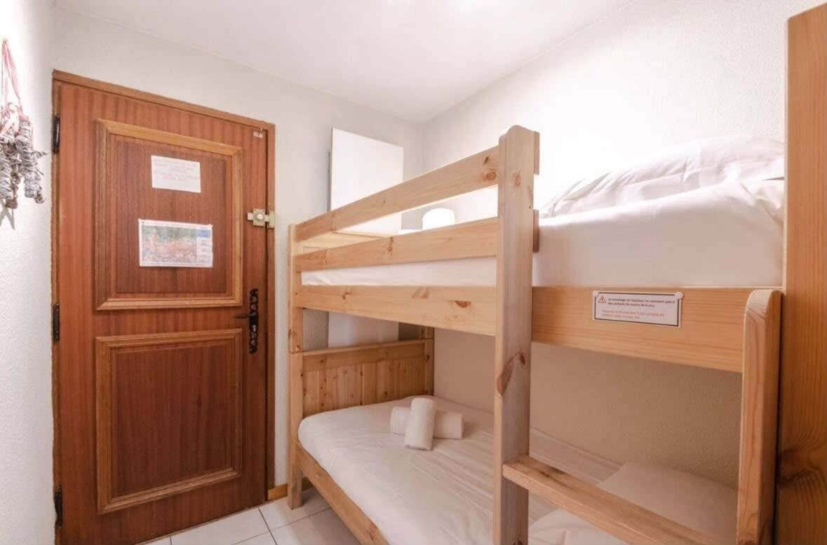 Une chambre avec un lit superposé, une porte en bois et une petite affiche accrochée à la porte.