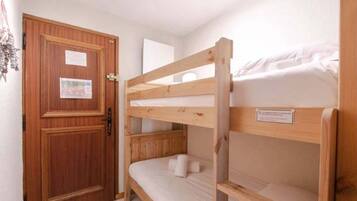 Une chambre avec un lit superposé, une porte en bois et une petite affiche accrochée à la porte.